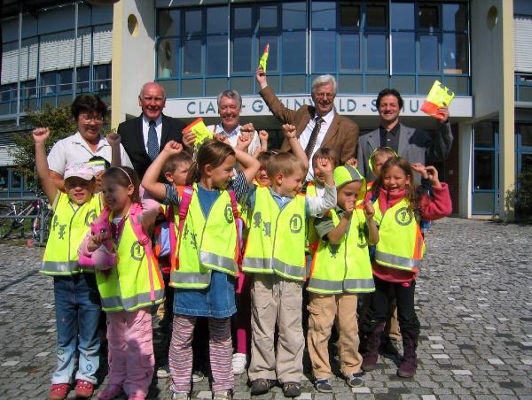 Da kommt Freude auf: Einige Erstklässler der Clara-Grunwaldschule in Freiburg jubeln über ihre neuen Sicherheitswesten. Ingrid Buttmi (Schulleiterin), Volker Mattern (Vorsitzender ADAC Südbaden), Sigrid Jürß (Niederlassungsleiterin Deutsche Post AG, Freiburg), Otto Neideck (Erster Bürgermeister der Stadt Freiburg) sowie Mario Schmid (Elternbeiratsvorsitzender) freuen sich mit.                                             Bild: ADAC Südbaden