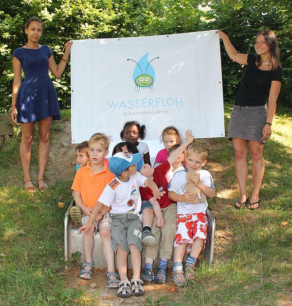 Kindergartenleiterin Katja Tavman (rechts) und Renée Fofana (links) mit präsentieren mit den Kindern des Schulkindergartens das neue „Wasserfloh“-Logo. Kindergartenleiterin Katja Tavman (rechts) und Renée Fofana (links) mit präsentieren mit den Kindern des Schulkindergartens das neue „Wasserfloh“-Logo.
